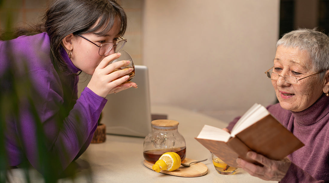 Elderly lady and a young woman sat having a nice cup of ginger tea together.