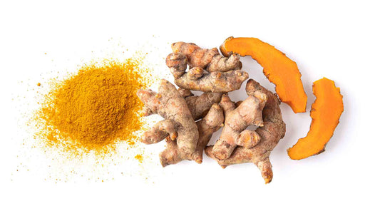 Whole ginger and turmeric root pieces sliced on a white background.