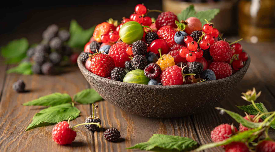Mixed berries and gooseberry in a wooden bowl on a wooden table.