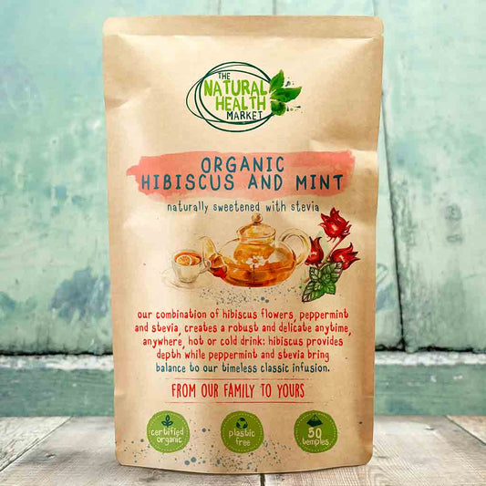 Pack of Organic Hibiscus and Mint tea bags from The Natural Health Market on a wooden surface with a blurred background.