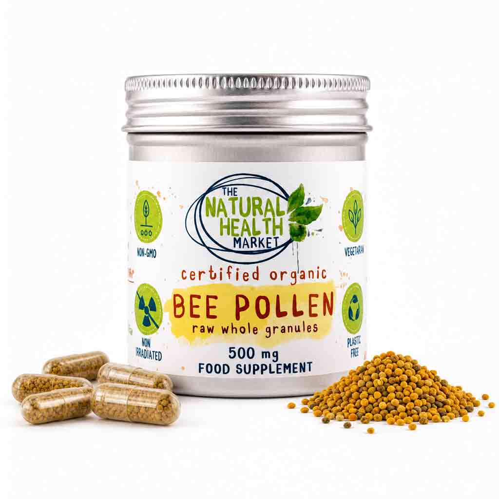 A tin of bee pollen food supplement with a silver metal lid and a white label reading 'The Natural Health Market' and 'Certified Organic Bee Pollen'. Several clear capsules filled with yellow-brown pollen are placed on the left, and a small pile of loose bee pollen granules is on the right, all on a clean white background.