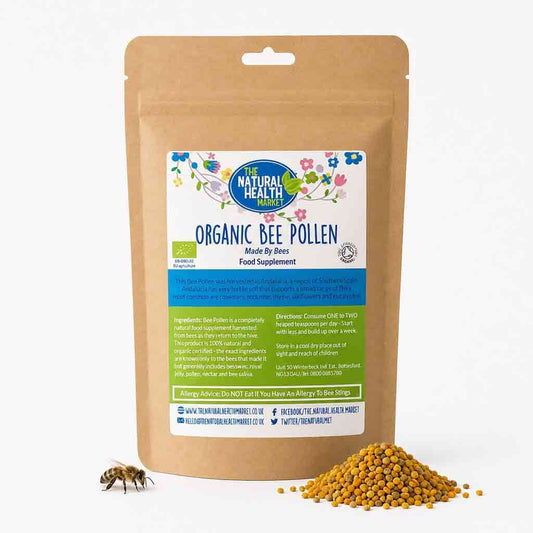 A stand-up kraft paper pouch of The Natural Health Organic Bee Pollen food supplement, shown on a white background with a small bee and a pile of yellow pollen granules in front.
