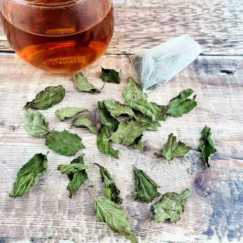 Organic Peppermint tea Bags by The Natural health Market - with fresh whole peppermint leaves and a cup of tea.