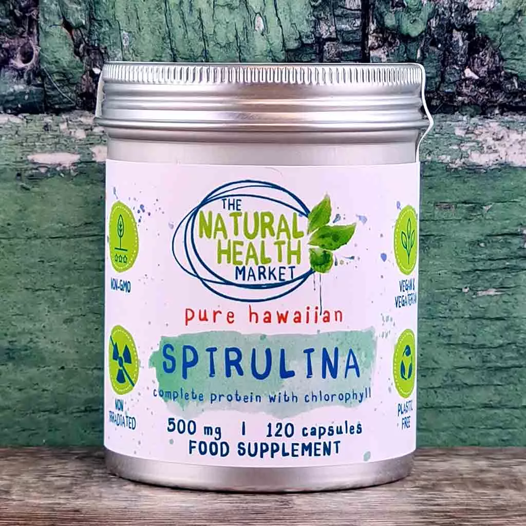 A tin of hawaiian spirulina capsules 120 capsule pack on a rustic wooden board.