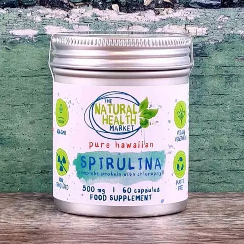 A tin of hawaiian spirulina capsules 60 capsule pack on a rustic wooden board.