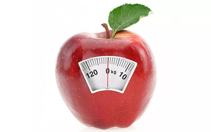 An apple with a a single green leaf with a weighing scales.