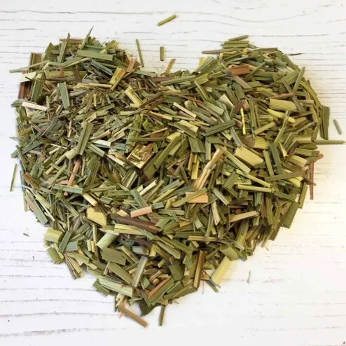 A heap of cut organic lemongrass shaped like a heart on a white background.