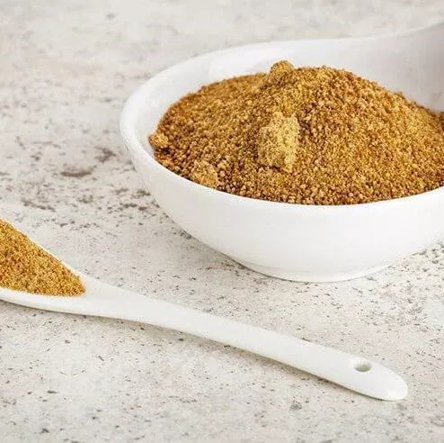 A white bowl filled with organic coconut sugar and a white spoon.
