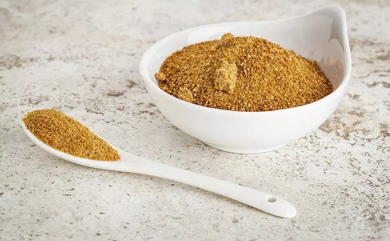 A white bowl filled with organic coconut sugar and a white spoon.