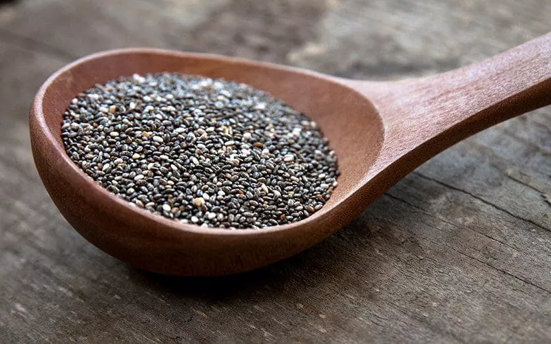 A wooden spoon filled with chia seeds.